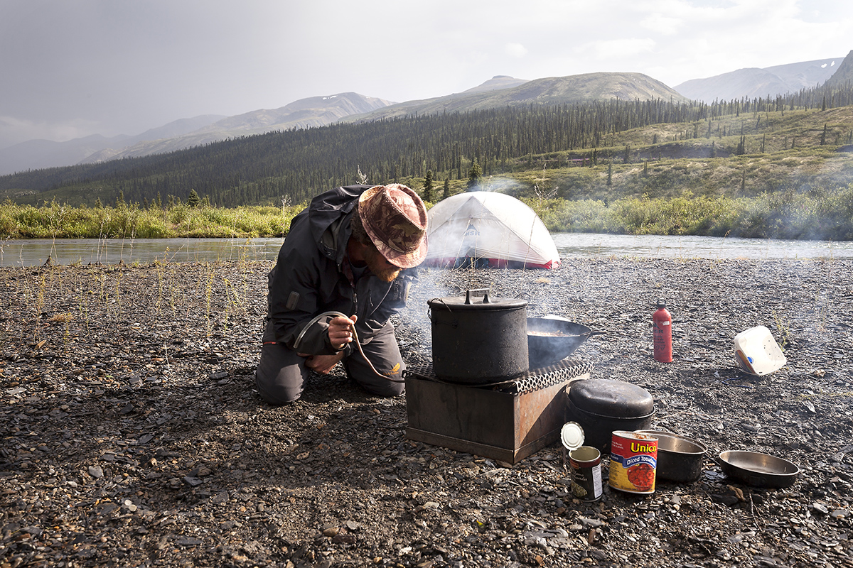 A member of the team cooks dinner on a firebox in Nahanni National Park.