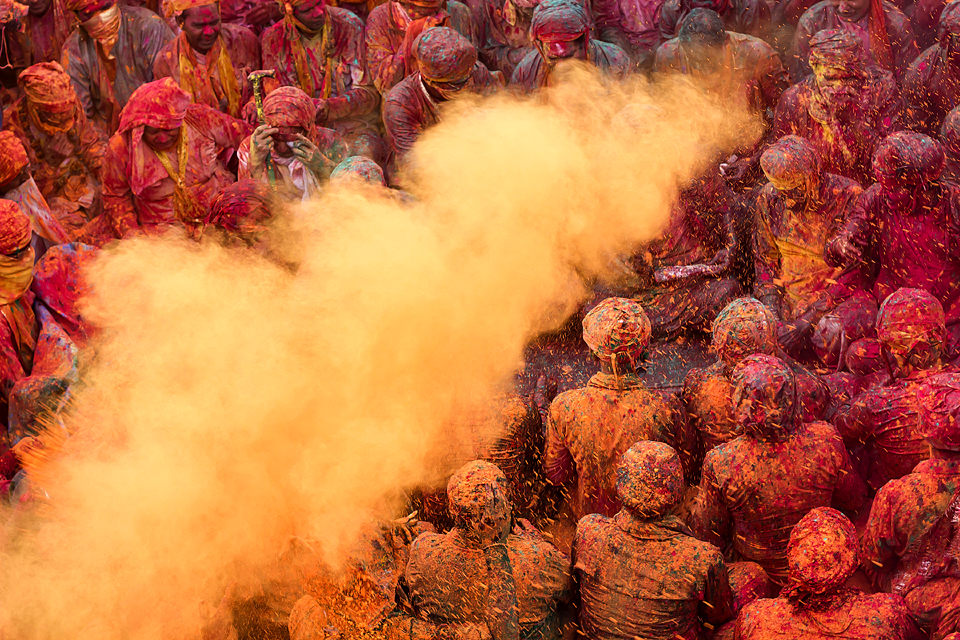 A man throws dry colour over the men folk to celebrates the unique 'Holi' at Nandgaon,  Uttar Pradesh.