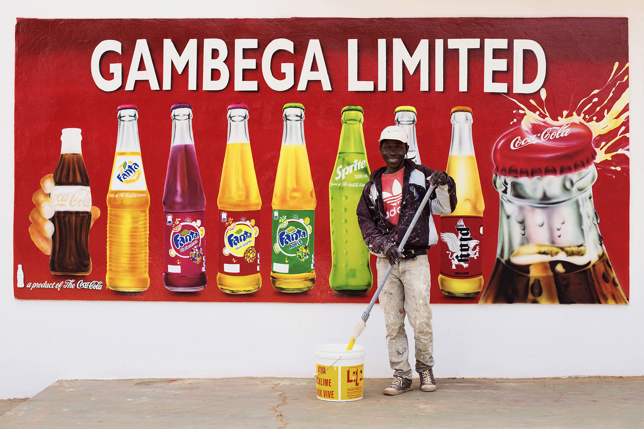 A Gambian man works painting advertisements on the walls of Serrekunda (the capital).