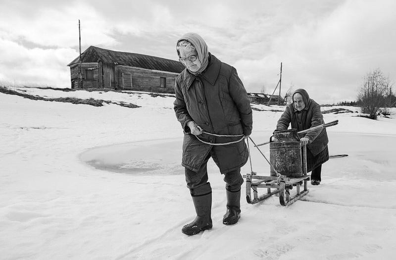 Alla Travina and Nina Udalova pull sleds with a can of river water.
