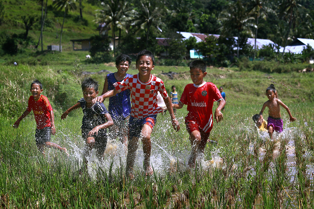 Children run gleefully across a field that will soon be used for the next Pacu Jawi race. Now, these races have become a world-known spectacle.