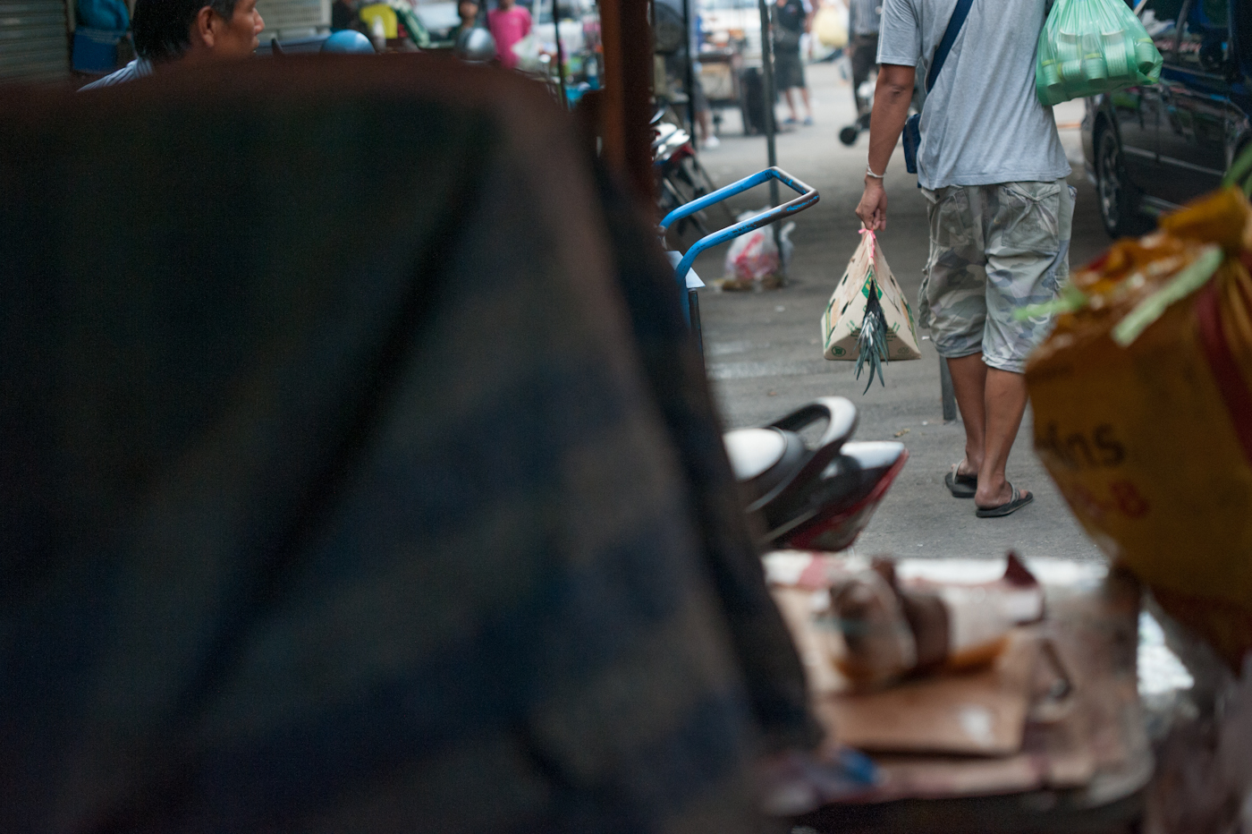 Chatuchak Weekend Market, Bangkok, Thailand 2012 An owner of a fighting cock leaves after a lost fight, carrying the animal in a cardboard bag.