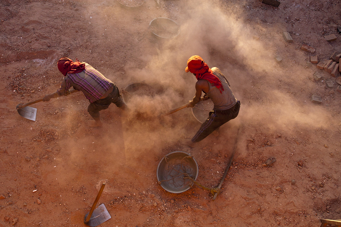 Labourers collect dust from the bottom surface of the oven in brick factory. The dust is re-used to cover the outer surface of the oven to protect heat from escaping while bricks are combusted inside the oven. People from India travel to Nepal to carry out this work including technical works in the brick factories in Nepal.