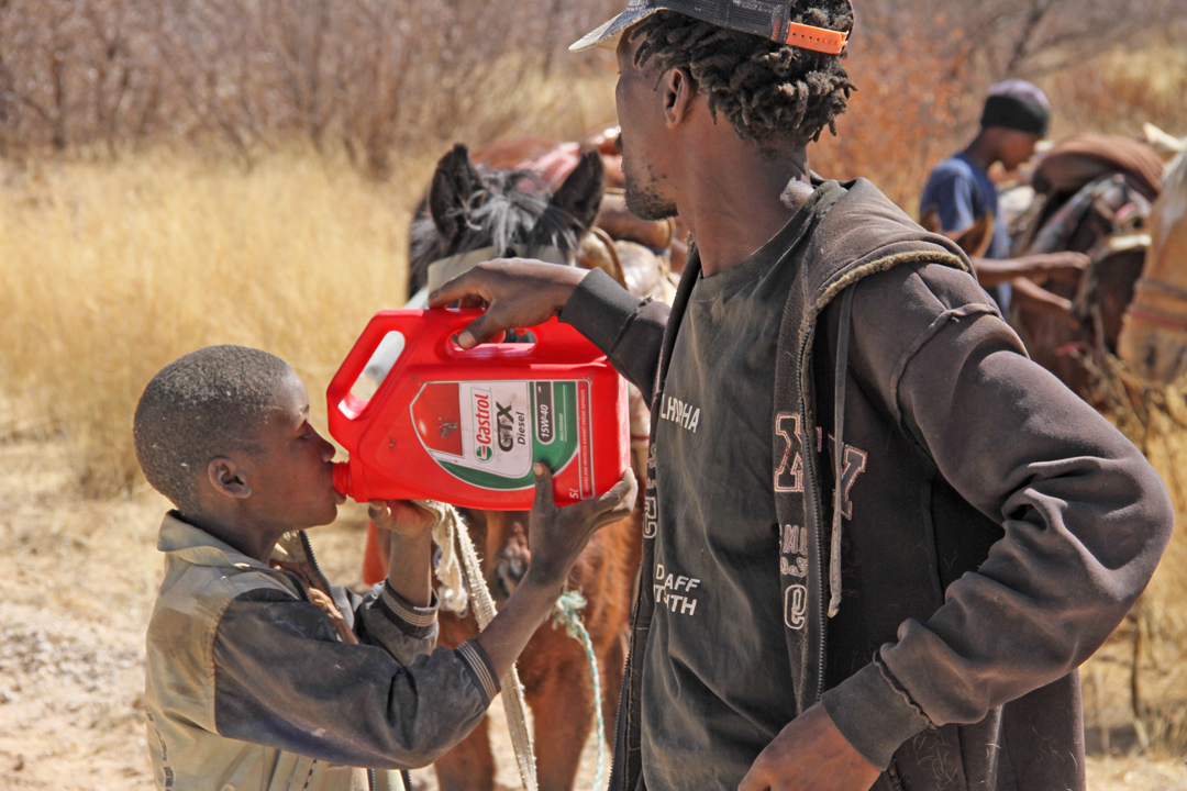 Quenching the thirst.....A young boy of Ranyane settlement in the Kgalagadi desert, West of Botswana, is assisted to drink water stored in a Castrol GXT diesel container by one of bis relativesl