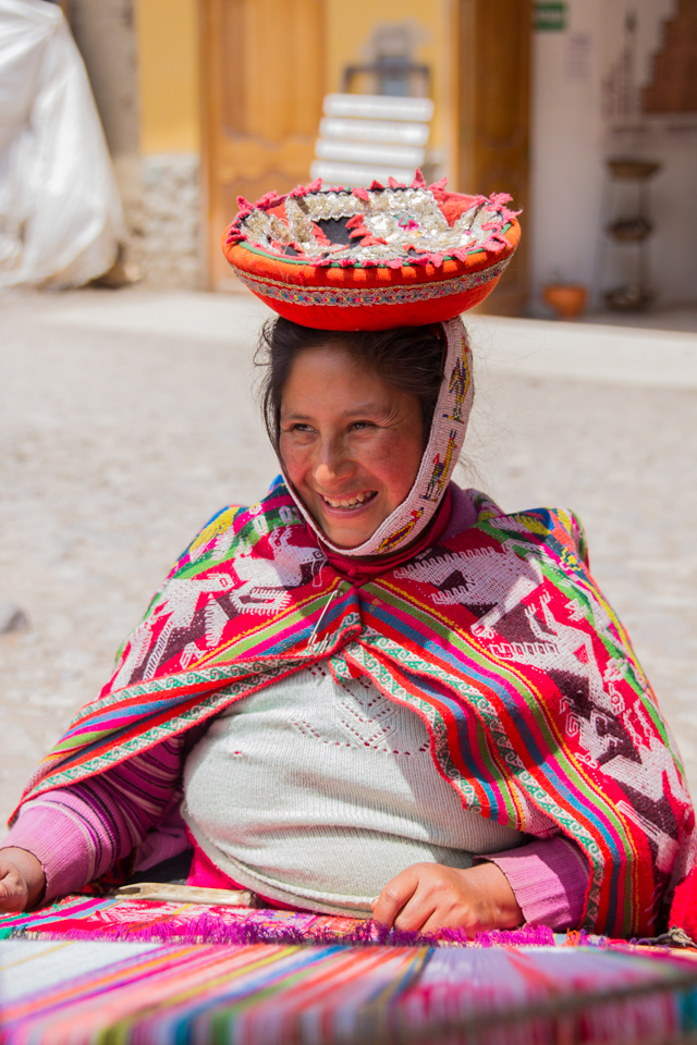 Here we see a young mother dressed in colourful traditional clothing who is also partaking in the ancient tradition of hand-woven crafts. Peru is well known for high quality textiles, hand-woven from 100% alpaca wool.