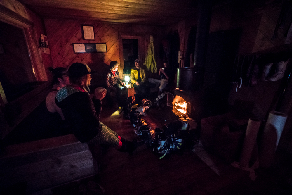 Sitting around the wood stove after a day of skiing at McNamara Hut. The common rooms of these public huts often serve as a place for groups to share adventures of the day and get to know one another.