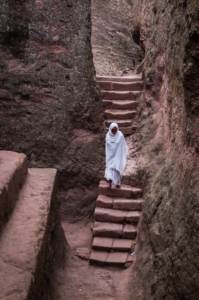 A woman climbs down the stairs on her way home. It's the worshipers who give life to the ancient rock walls. They live from their crops, their sheep and their faith, just like people have for thousands of years.