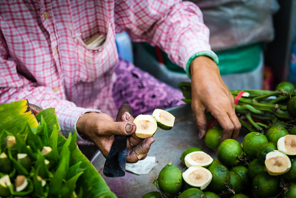 Preparing betel nut. The local nut is used like a chewing tobacco and stains the mouth and hands of those who prepare and use it.