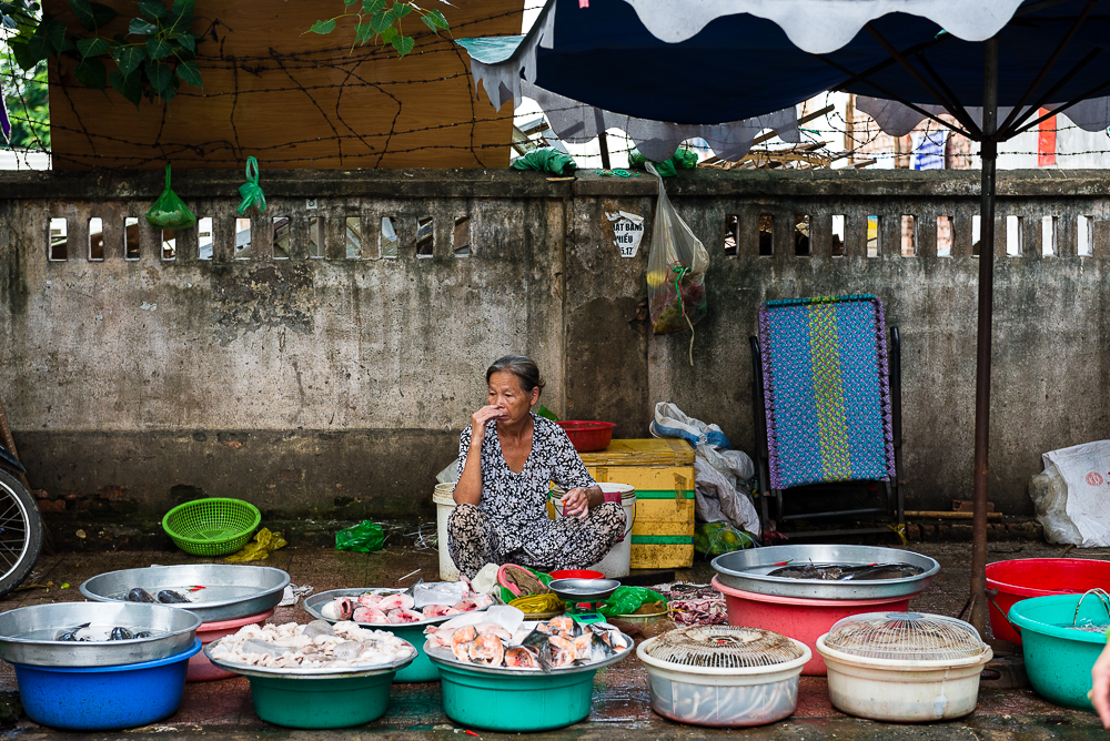 A woman sells fruits and vegetables by the roadside. Stallholders work from sunrise to sunset to earn their living.