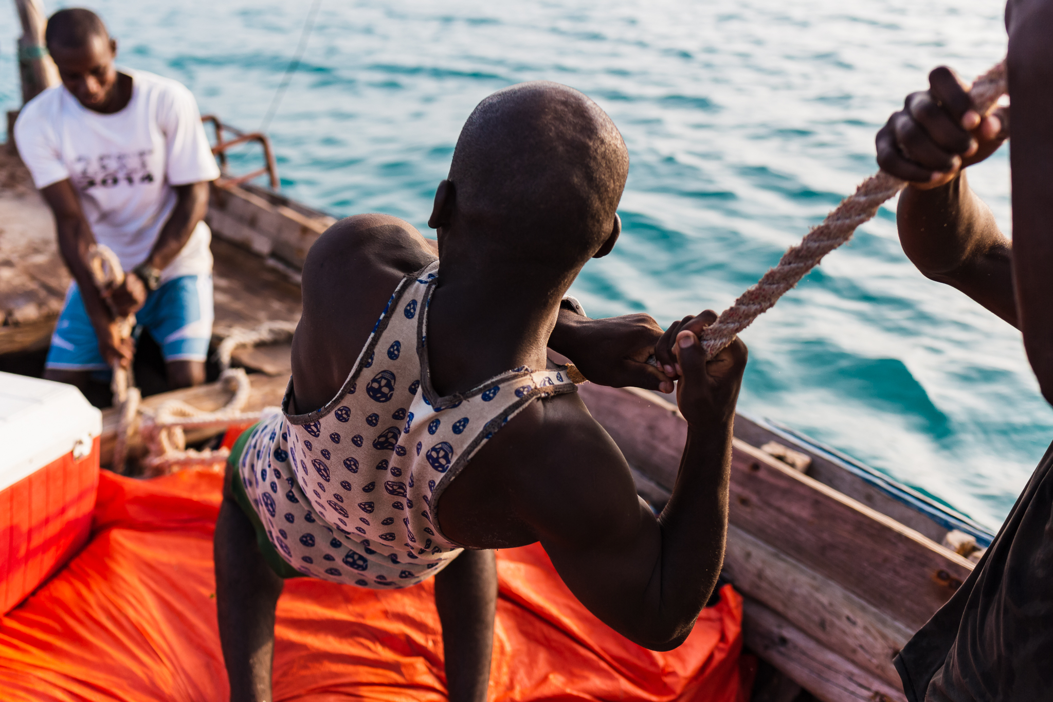 It takes all four men to keep the dhow sailing. Their craft is made of wood, iron, rope and canvas. The men are intimately familiar with dhow, like an old comfortable pair of shoes.
