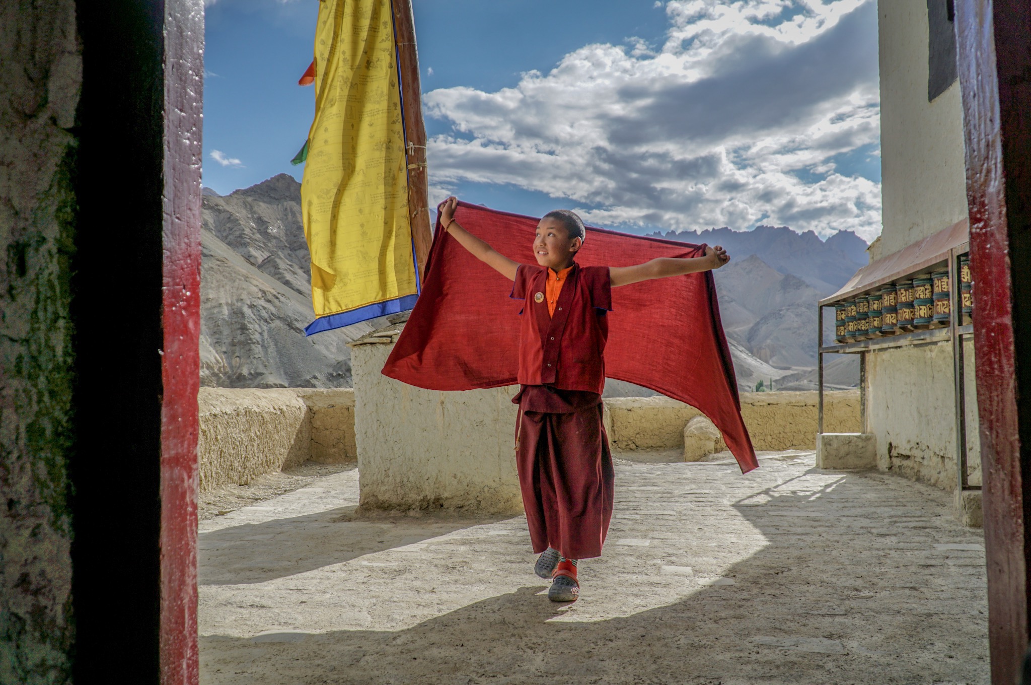 With the Himalayas in the background, this novice monk spreads out his arms.