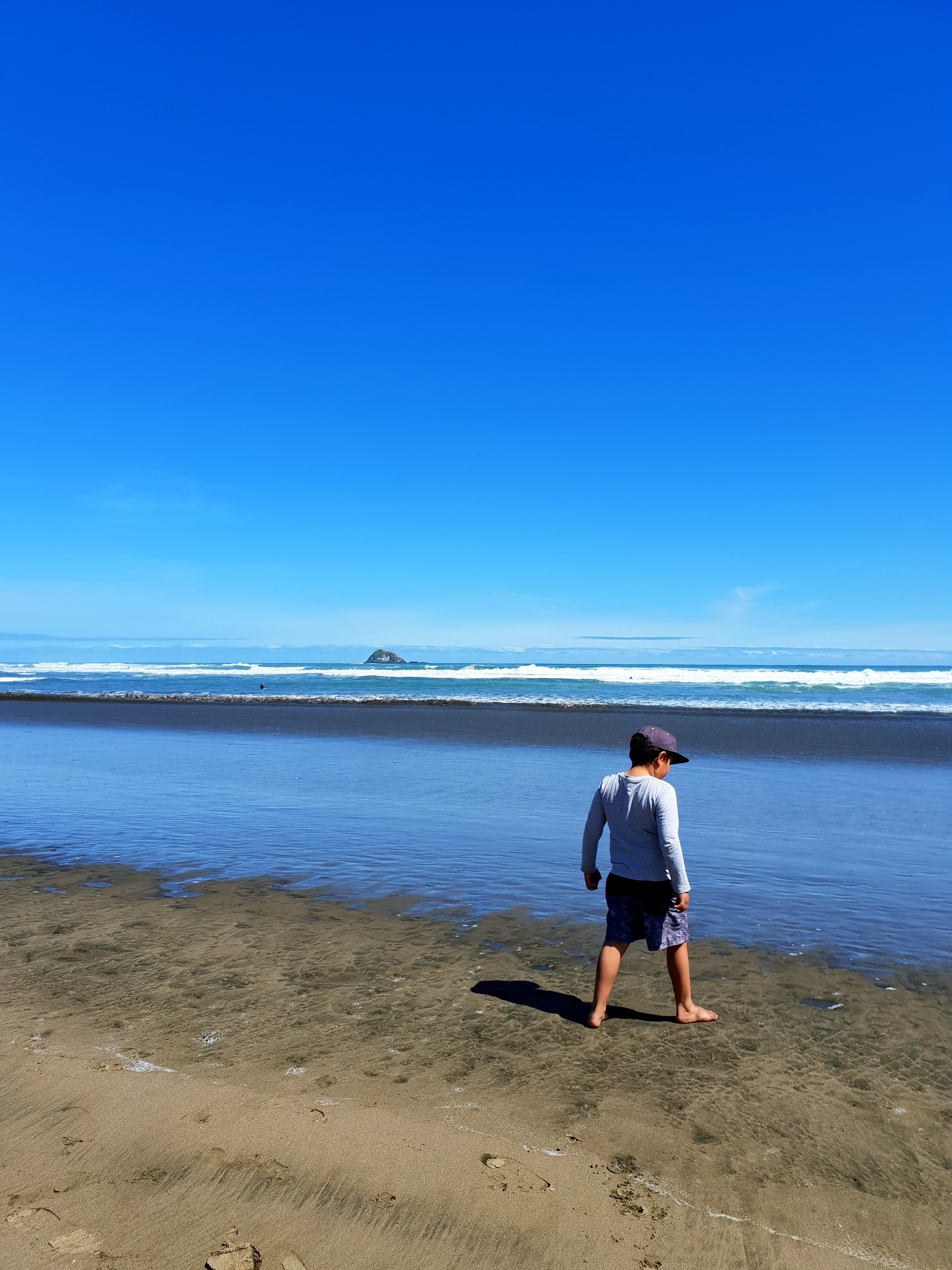 My son drawing in the black sands at Muriwai.