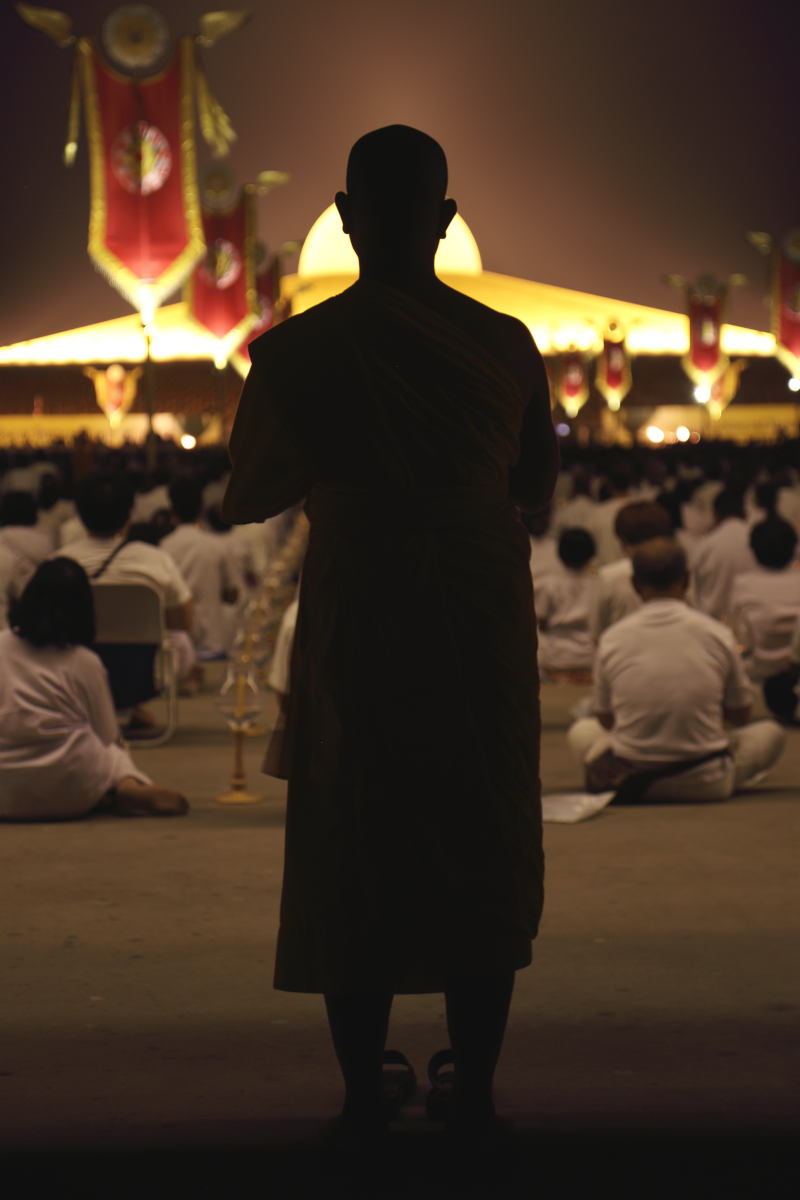 Monk on the outer rim, facing the domed structure with an exterior comprised of 300,000 Buddha statues.