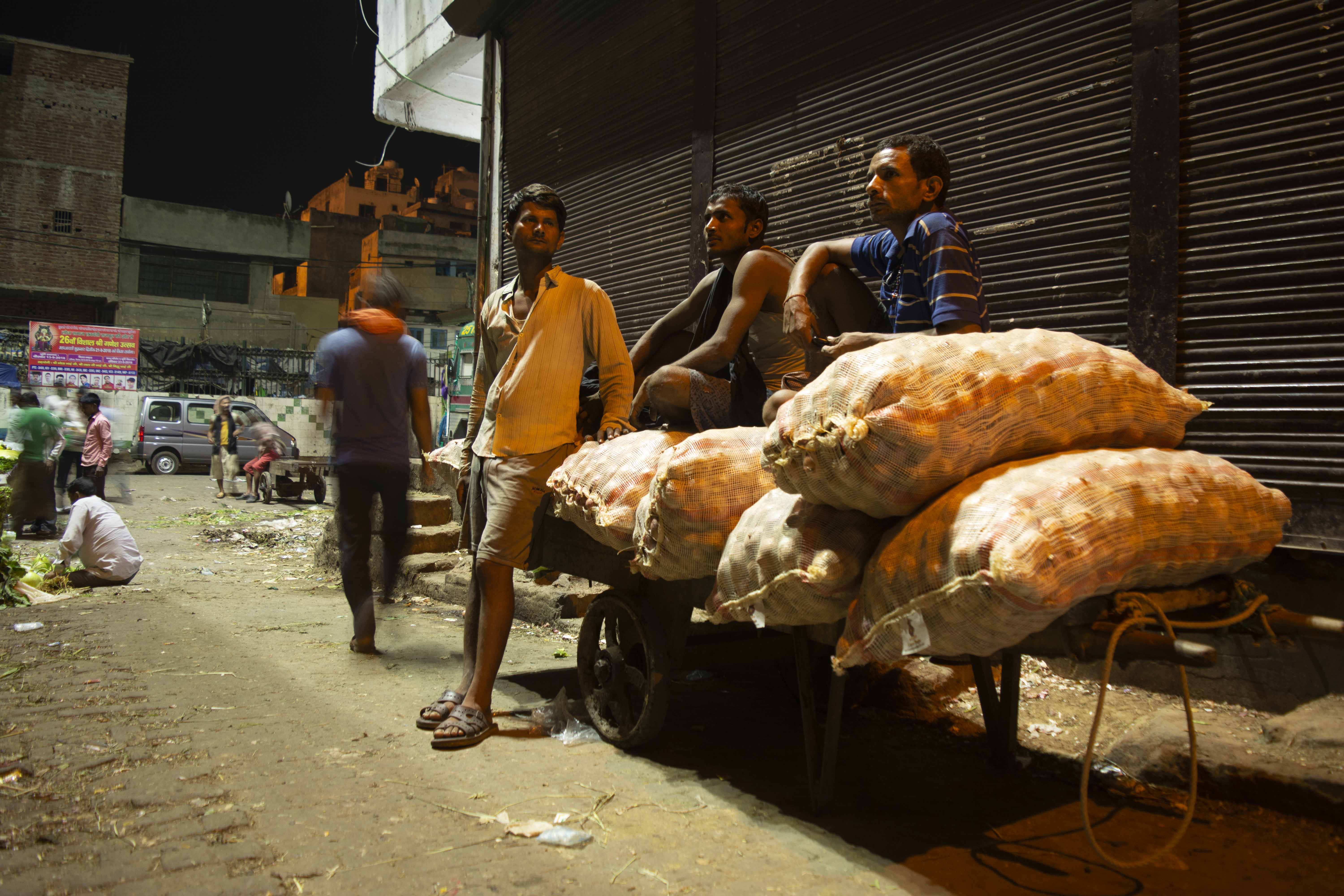 These daily wagers are safekeeping the vegetable sacks and the waiting for the people to load it back to the trucks for transportation.