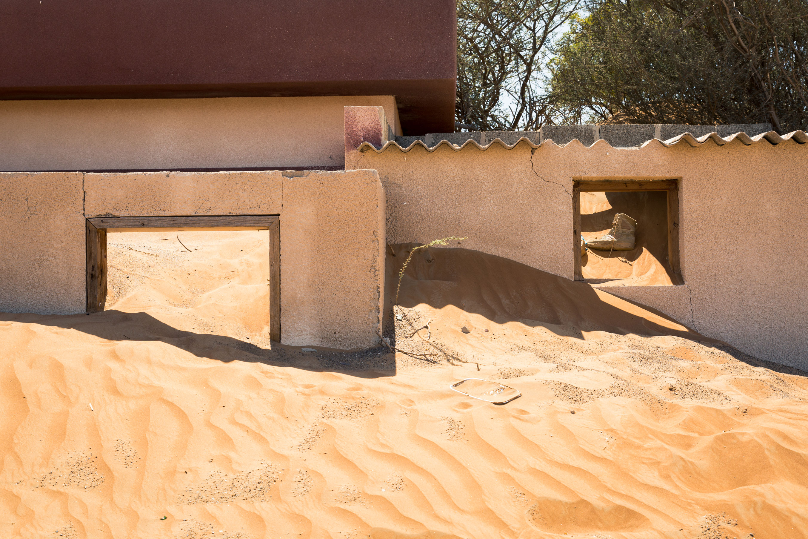 The hot Arabian Desert sand slowly overtakes one of many homes in this abandoned village. Although abandoned it is not forgotten, as evidenced by traces of ongoing human activity and items left behind.