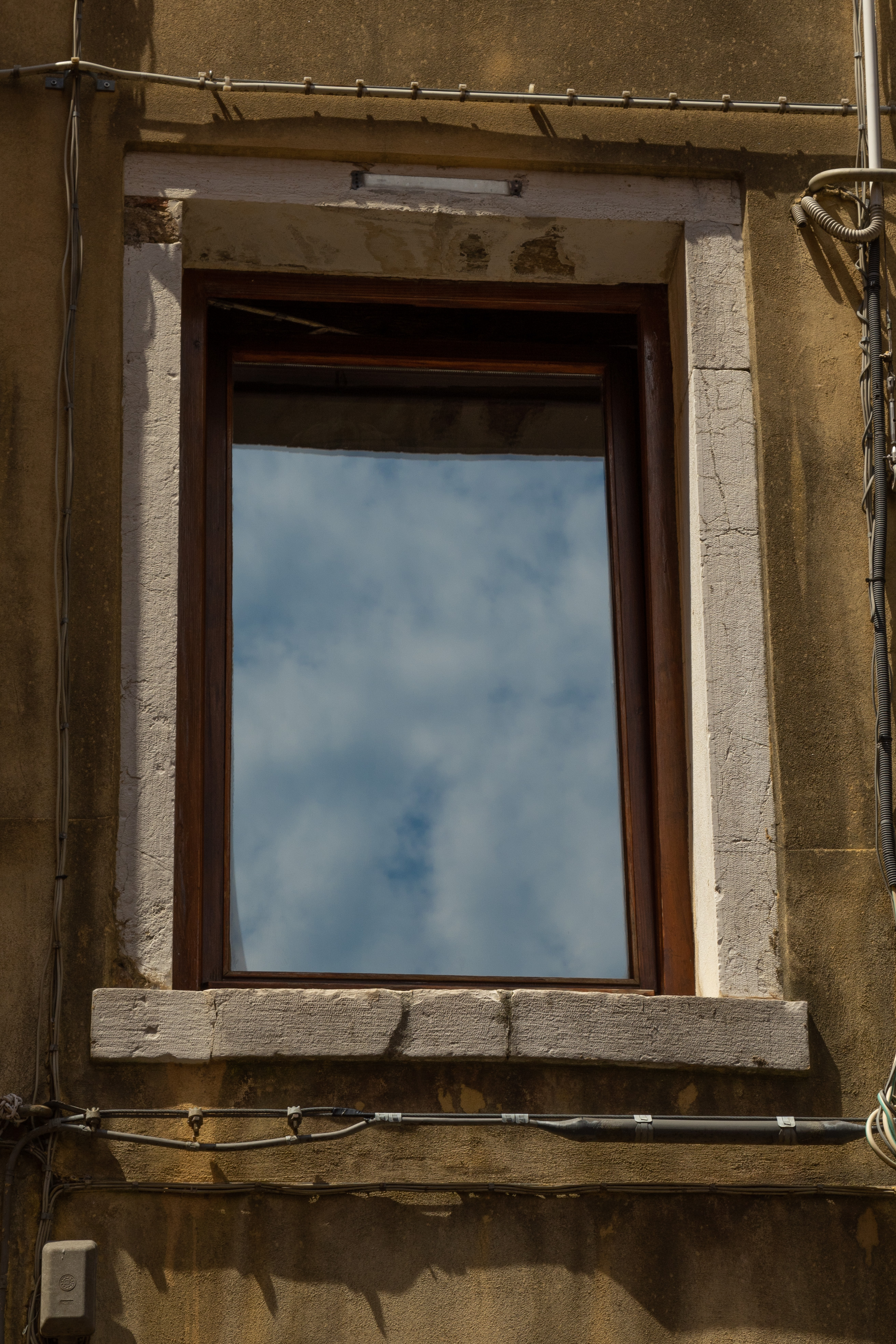 Old window reflecting sun, Italy