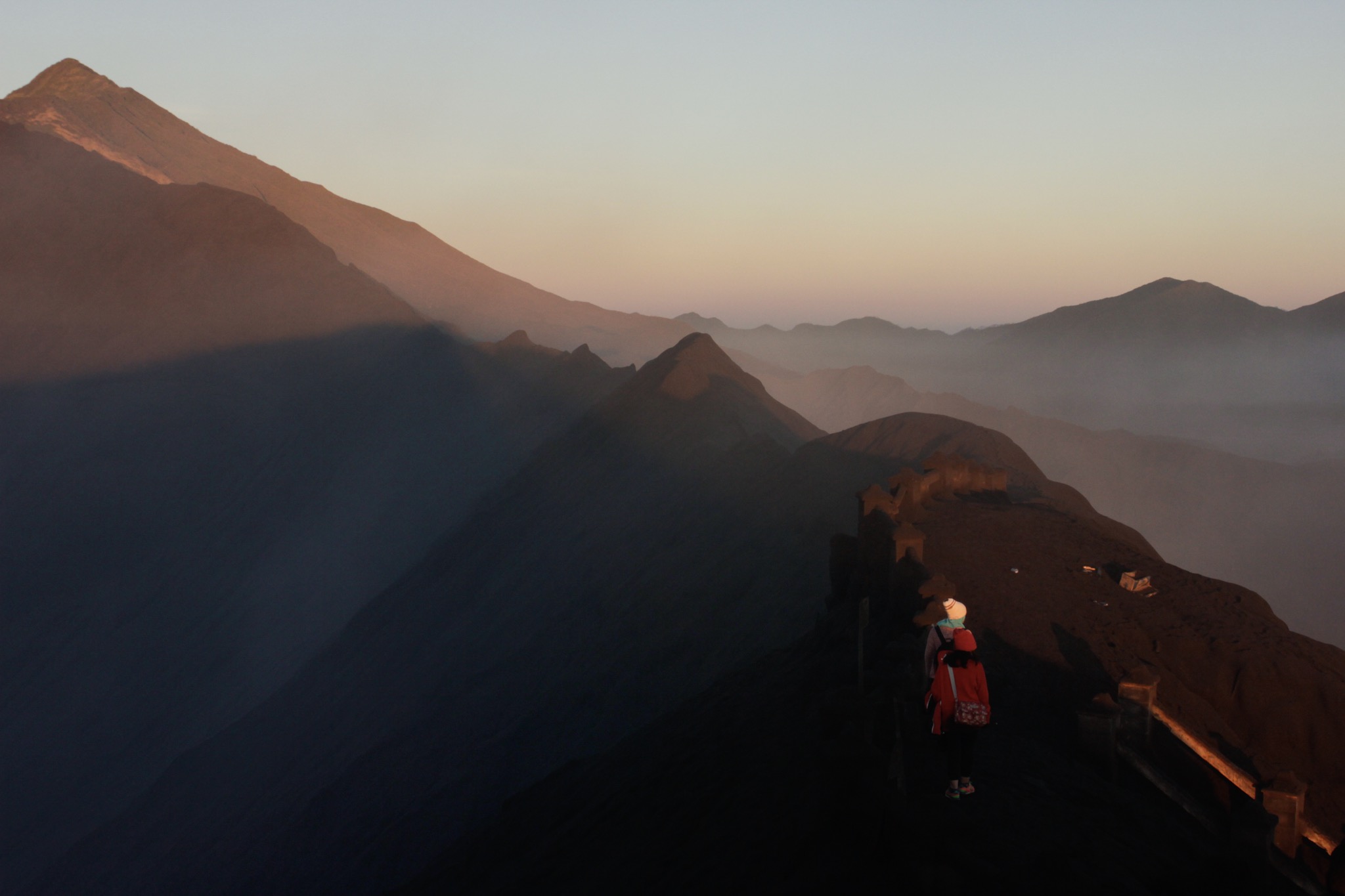 The Indonesian island of Java is almost entirely of volcanic origin, contains numerous volcanoes, Mount Bromo is one of those 45 volcanoes which are considered active (In frame: tourist walks on edge of crater rim to find best spot for experiencing sunrise)