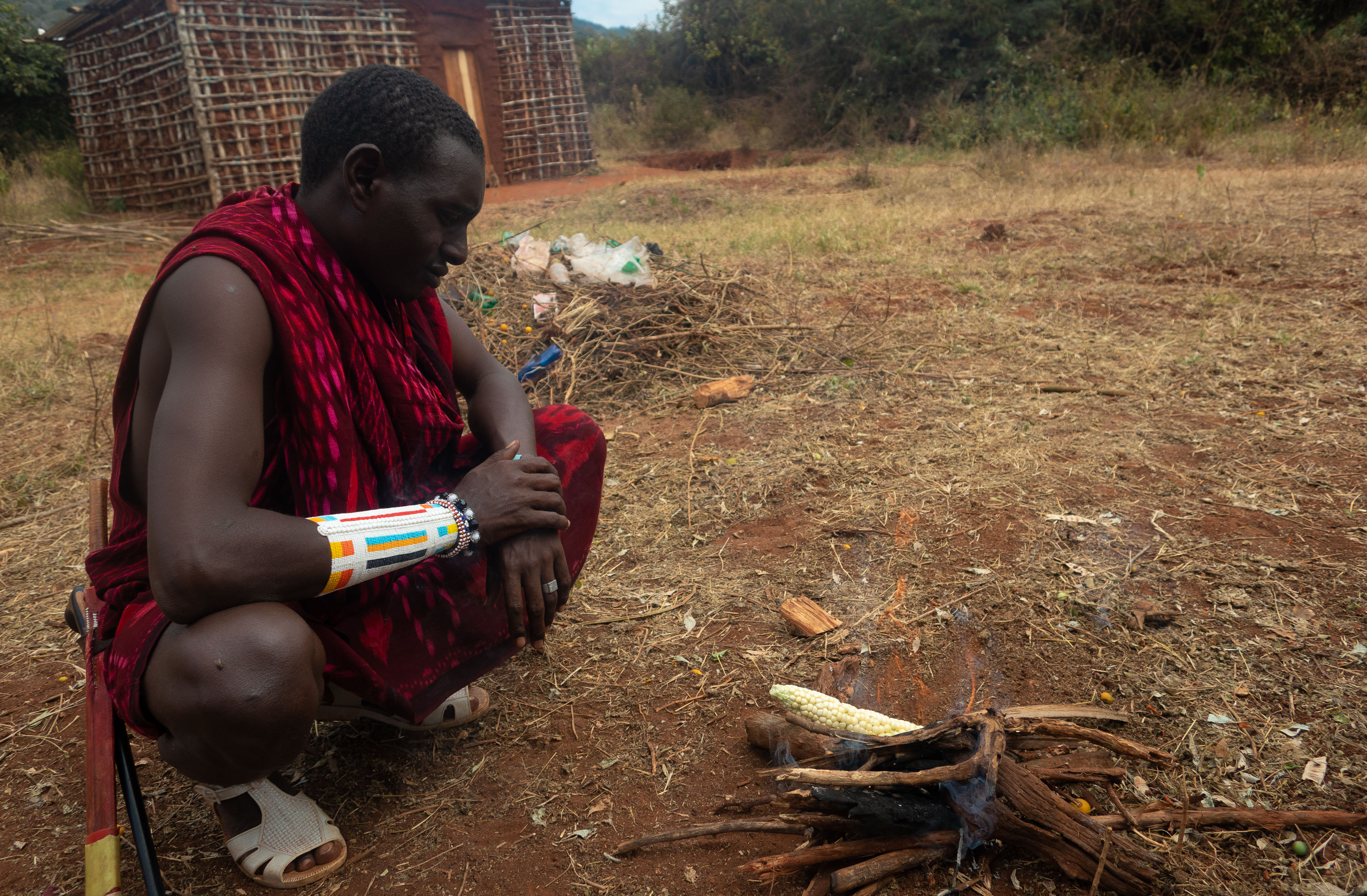 Maize: Matteo is roasting freshly picked maize, on a fire he made, in front of a pile of trash they will burn later. Maize is a primary crop of the Masai diet and they use it to make Ugali (a thick type of porridge), which is a staple food throughout Tanzania. 