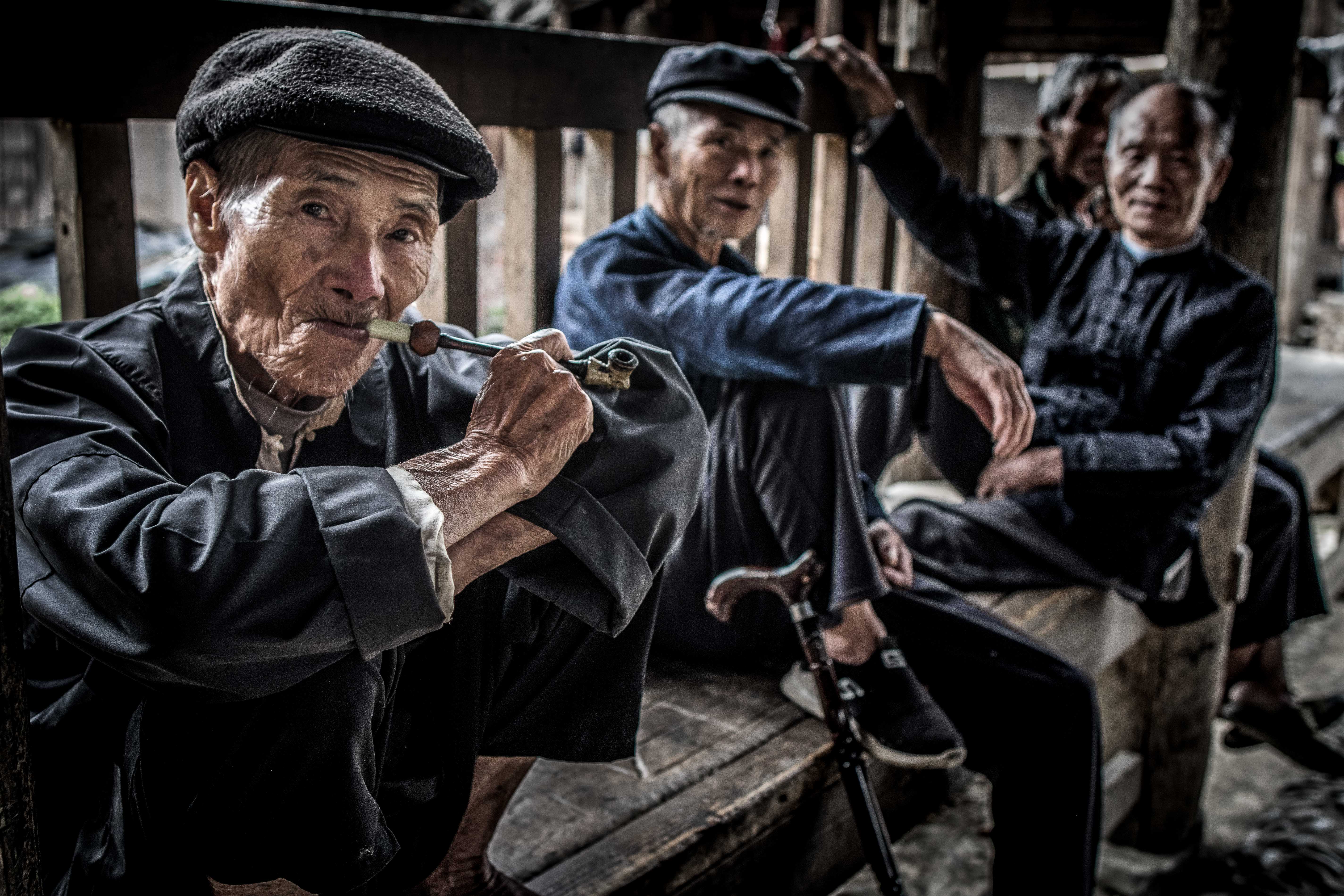 In Guizhou villages, old men mostly spend their time chatting and smoking pipe. Here there are some from the Dong ethnic group under the roof of a "wind and rain bridge".