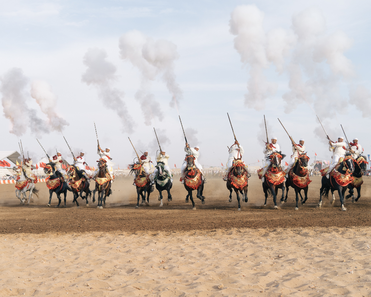 Fantasia horsemen shoot. All the group charges along a straight path at the same speed to form a line. Towards the end of the about-two-hundred-meters run they fire into the sky using their moukhalas: the complexity of the performance is the synchronicity of movements and shots by all the horsemen.