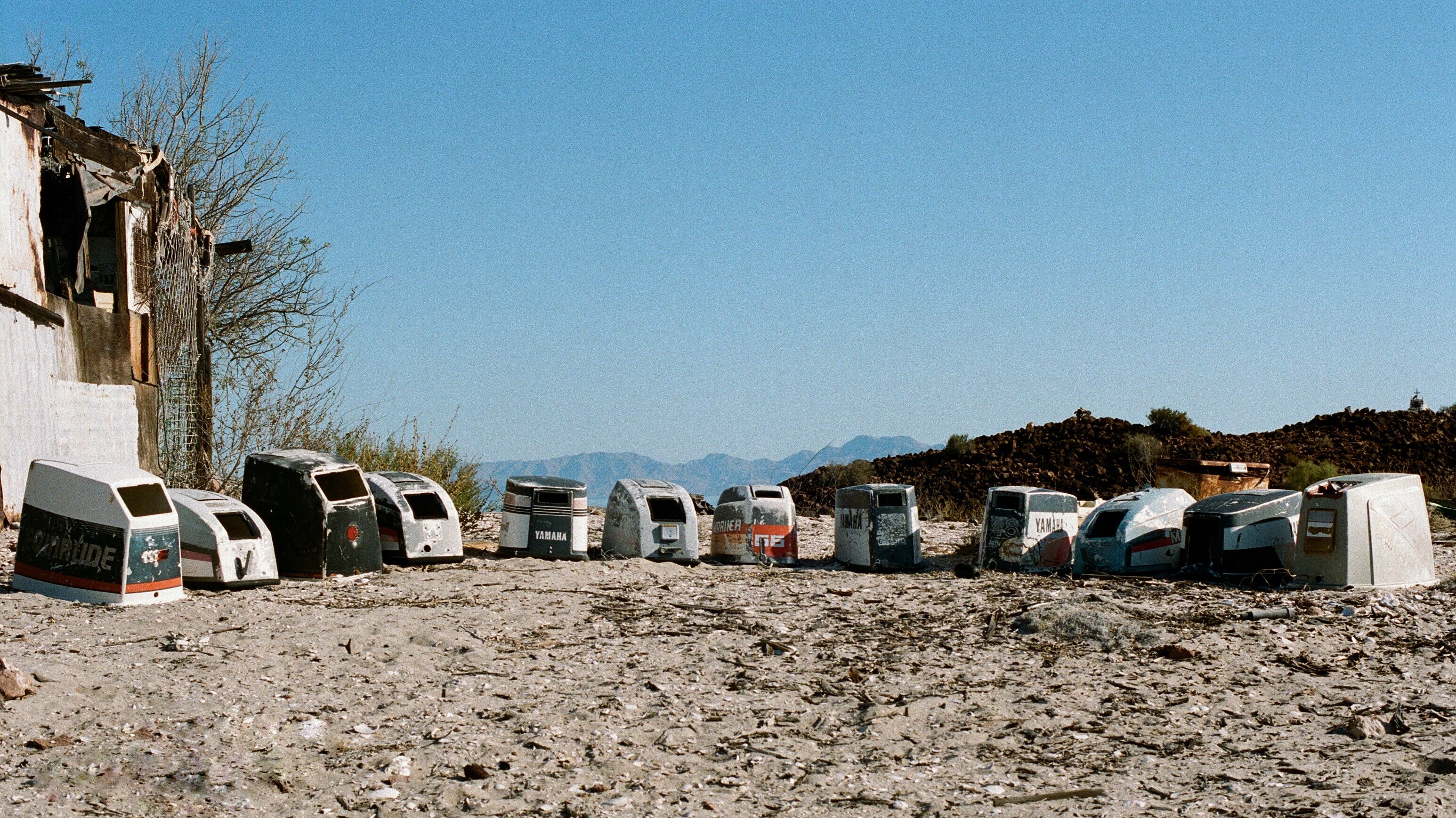Outboard motor covers arranged in a semi-circle in an abandoned fish-camp. The fishing industry in Baja, one of the main local sources of income, has declined due to overfishing and an emphasis on sport-fishing tourism.