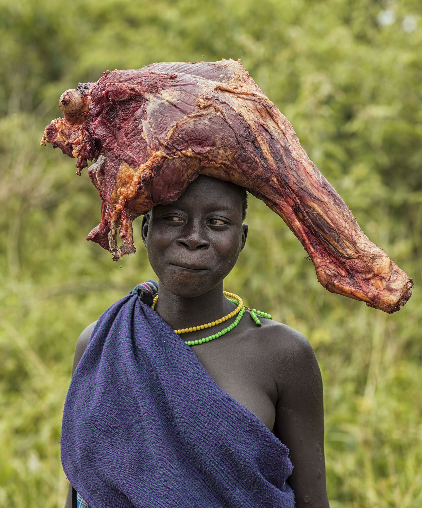 'Trip to the Butcher' - Suri share a border with Soth Sudanese tribes and there is often conflict. Cattle is often stolen or killed. To prevent this the Suri people keep there livestock many days walk away and out of danger. Pictured is girl who was on the walk back from the cattle camp.