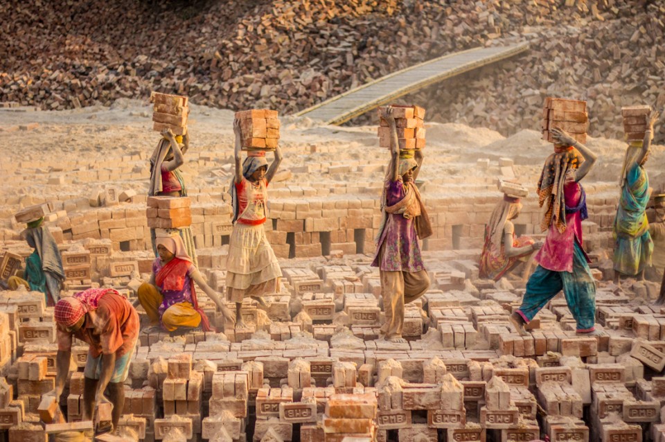 Group of girls carrying ready bricks out of the oven.