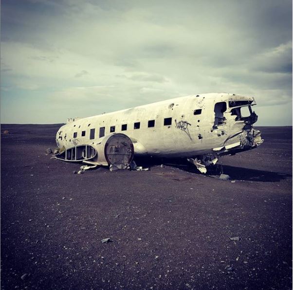 A plane wreck in the middle of a black sand beach