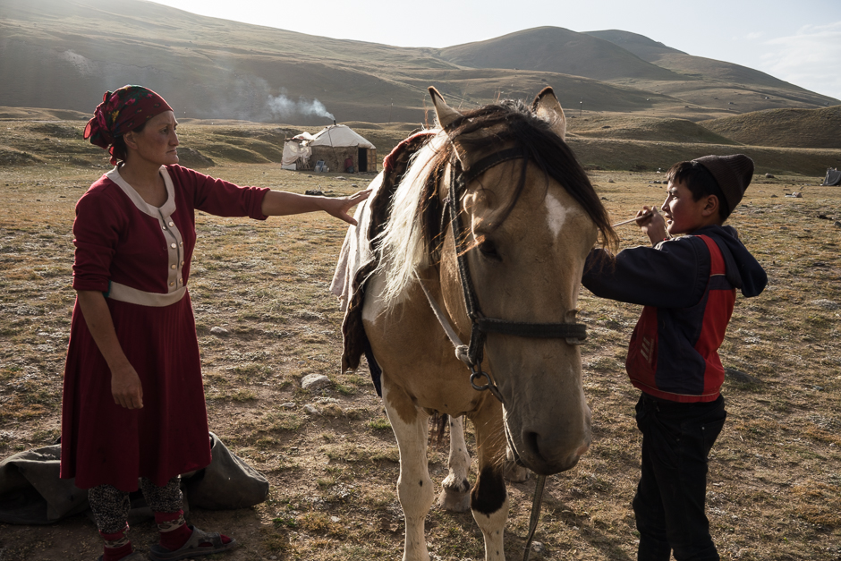 It’s the end of the day and before the sun sets Jangybai with the help of his mom needs to prepare their horse for an overnight stay at high altitude pasture. They put several blankets on the horse to protect it from cold.
