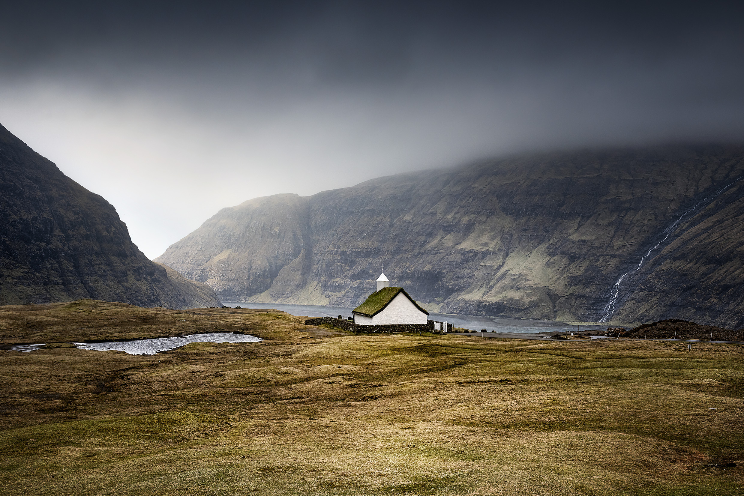 Saksun on Streymoy island, with lovely little church is a rremot village set in a natural circular amphitheatre high above a tidal lagoon. Mountains and ocean affects its weather, creating fantastic, moody atmosphere.