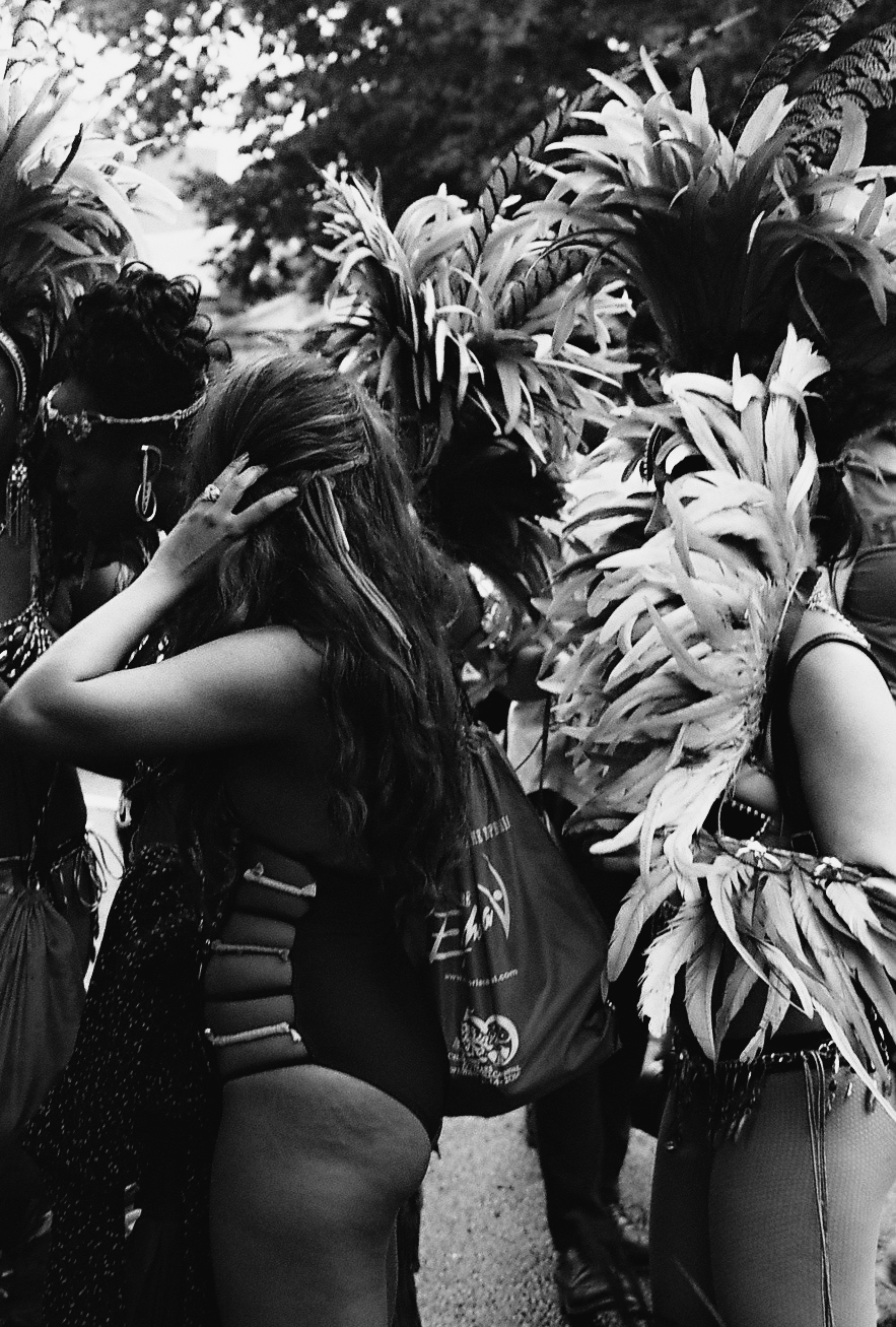 The feminine feathered women arrive at the mouth of the procession path. Prepping themselves and each other for their 2-day extravaganza ahead. Months of routines and rhinestones lead them to this celebration of life, love and heritage. 