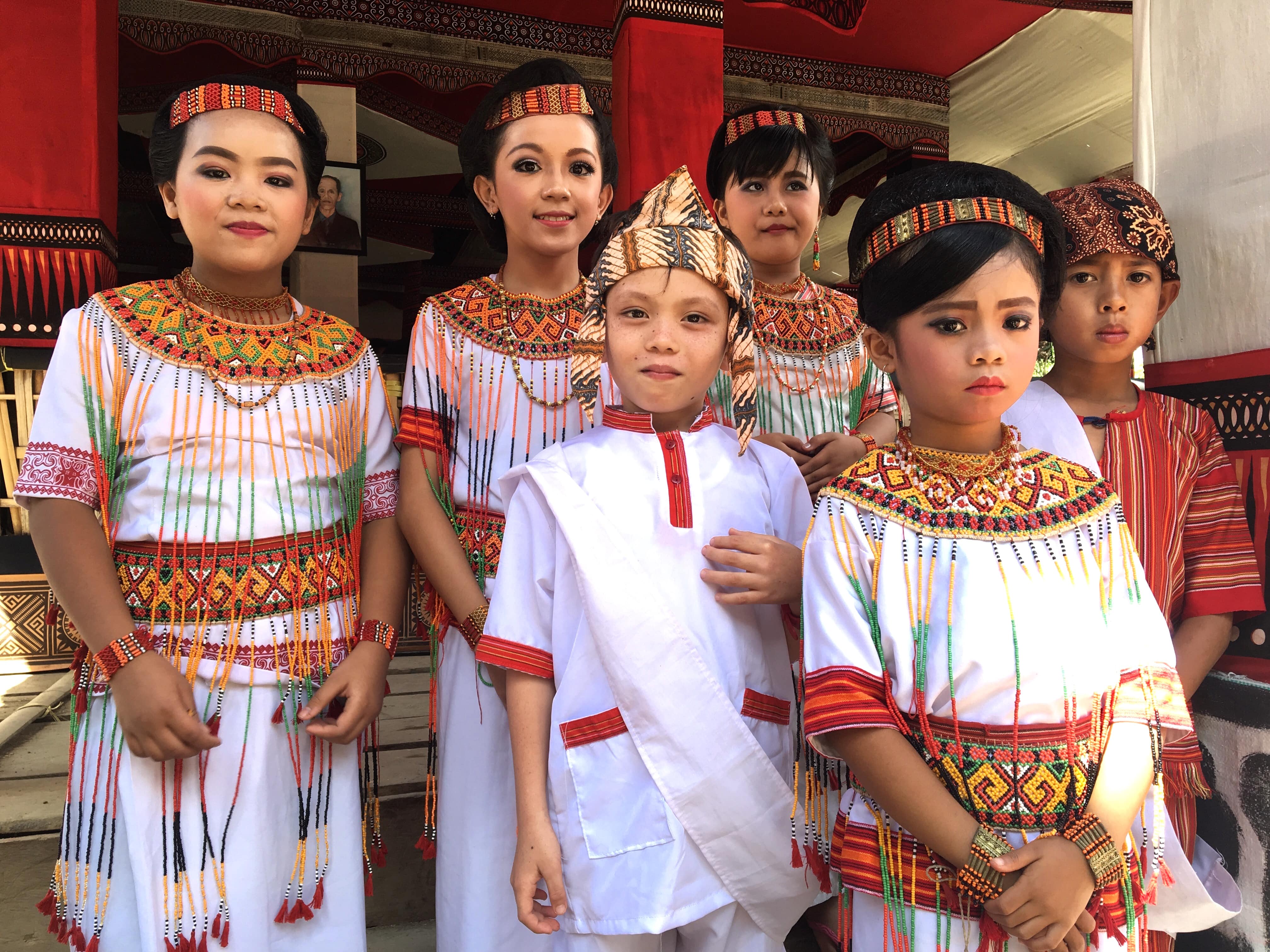Torajan children in costume prior to a funeral dance. Children are an important and common feature during funerals, representing rebirth in the next life; the motifs of their clothing convey special symbolism, as does the color white, in contrast to the traditional mourners’ black.