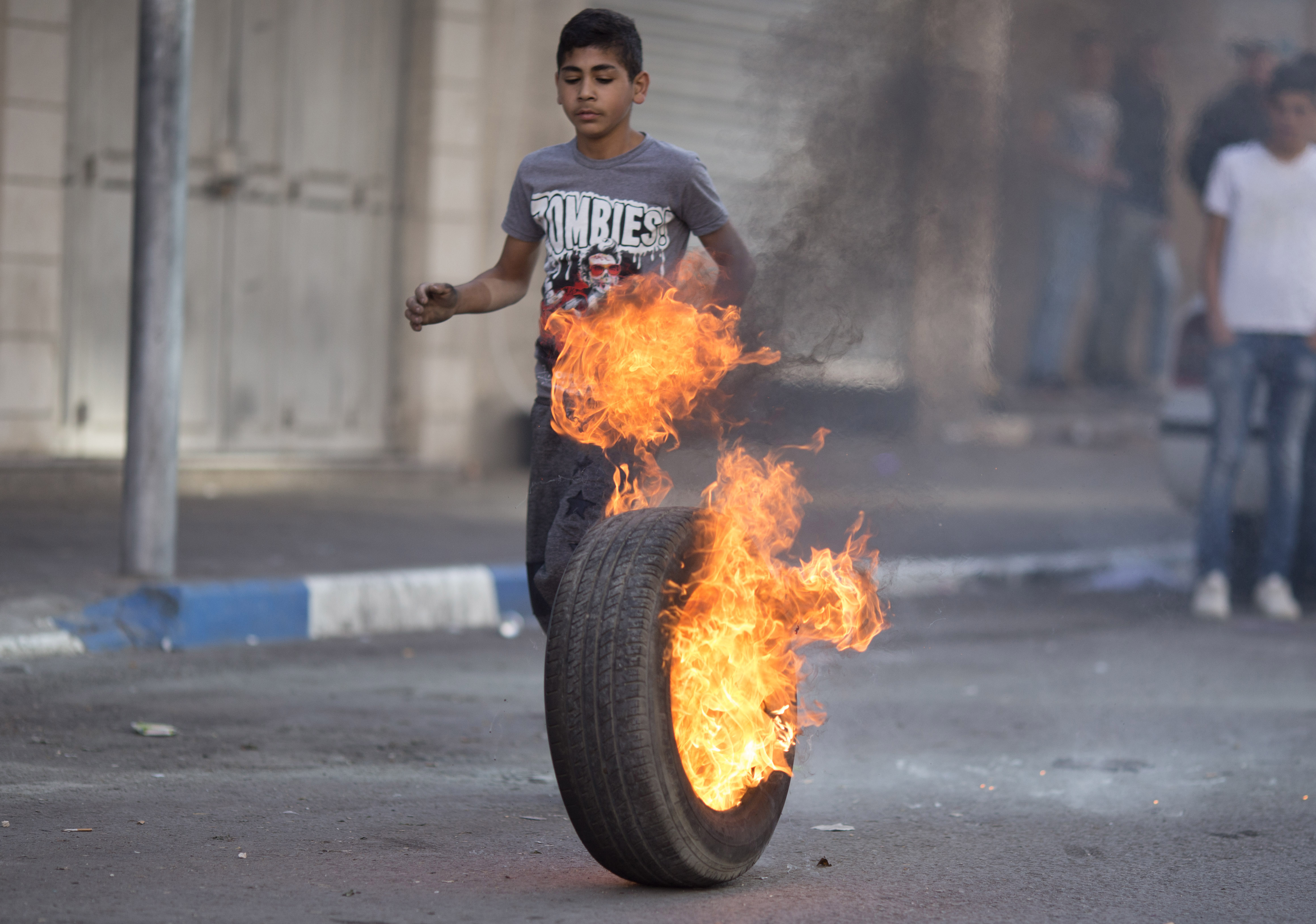 A child runs next to a burning tyre lit by protesters in the occupied city of Hebron. 