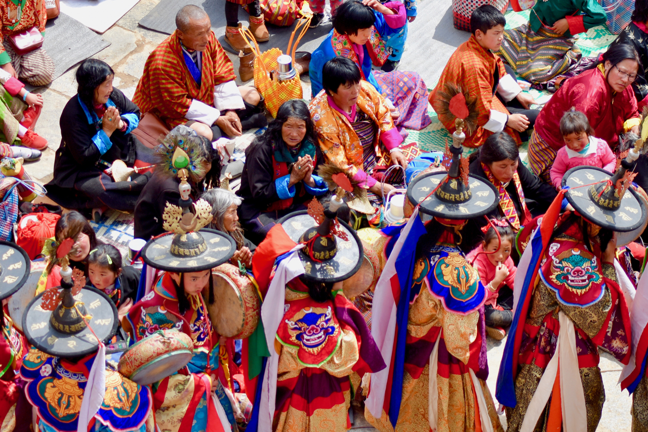 The Bhutanese don their finest traditional dress to attend the Tsechu, where sacred dances, called Cham, are performed by monks. Here, spectators reverently watch the arrival of the Black Hat dancers.