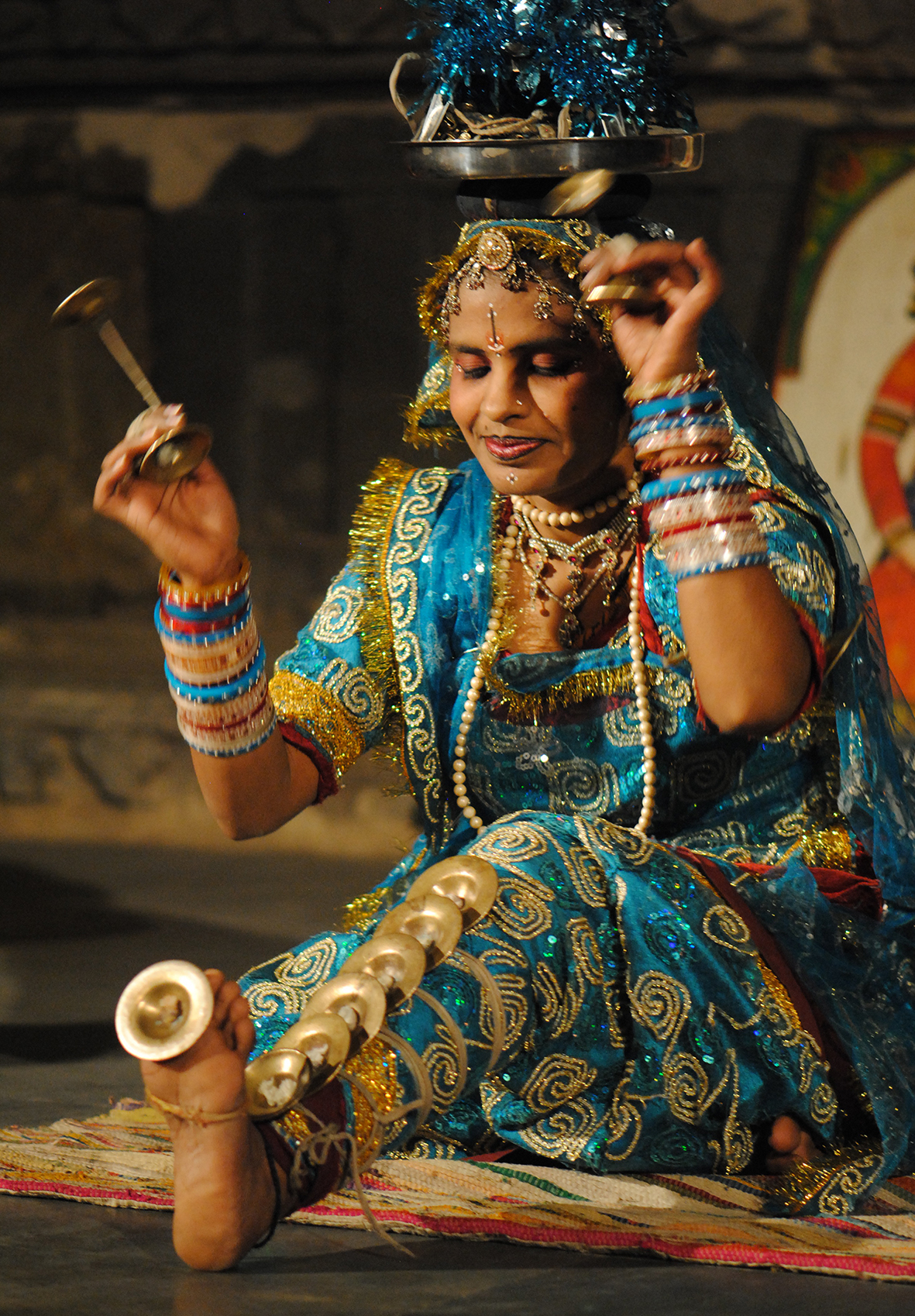 The folk Terah Taali dancer matches the background music by swinging the manjeeras (little brass disks) and striking the cymbals that are tied to different parts of her body.