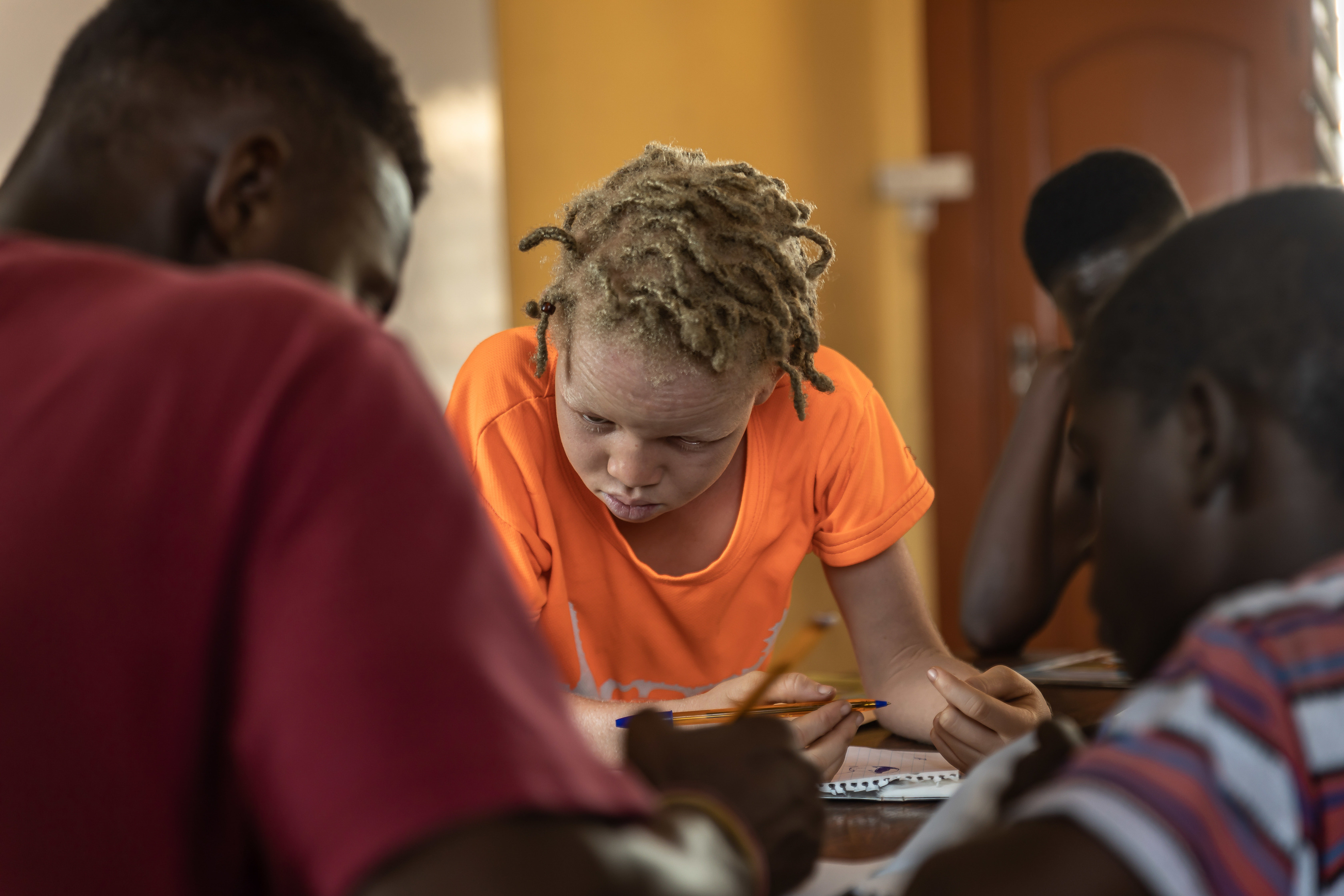 The organization’s after-school program provides small group lessons that focus on mathematics, English, and science. A little girl with albinism is seen here participating in the activities among other children. 