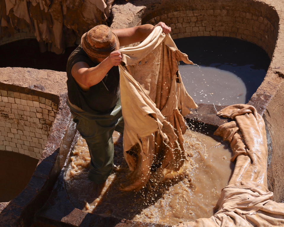 Hides are manually dyed by a worker standing in a vat of dye. The hides are soaked in the dye vat and, when the dye has been absorbed into a hide, the worker lifts it out and shakes off the excess dye. 