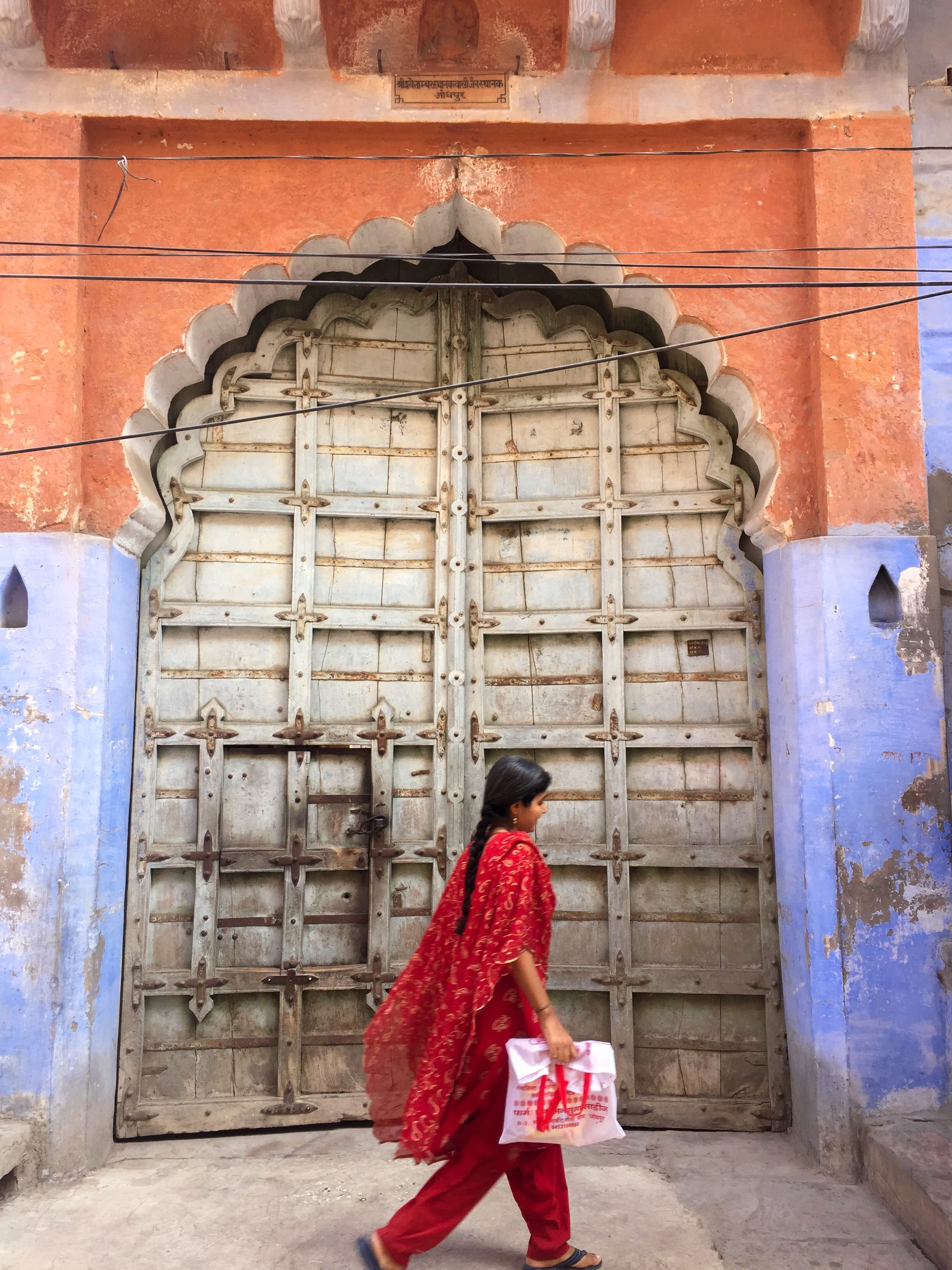 A young woman in a vermillion salwar kameez walks, unintentionally creating art with every step.