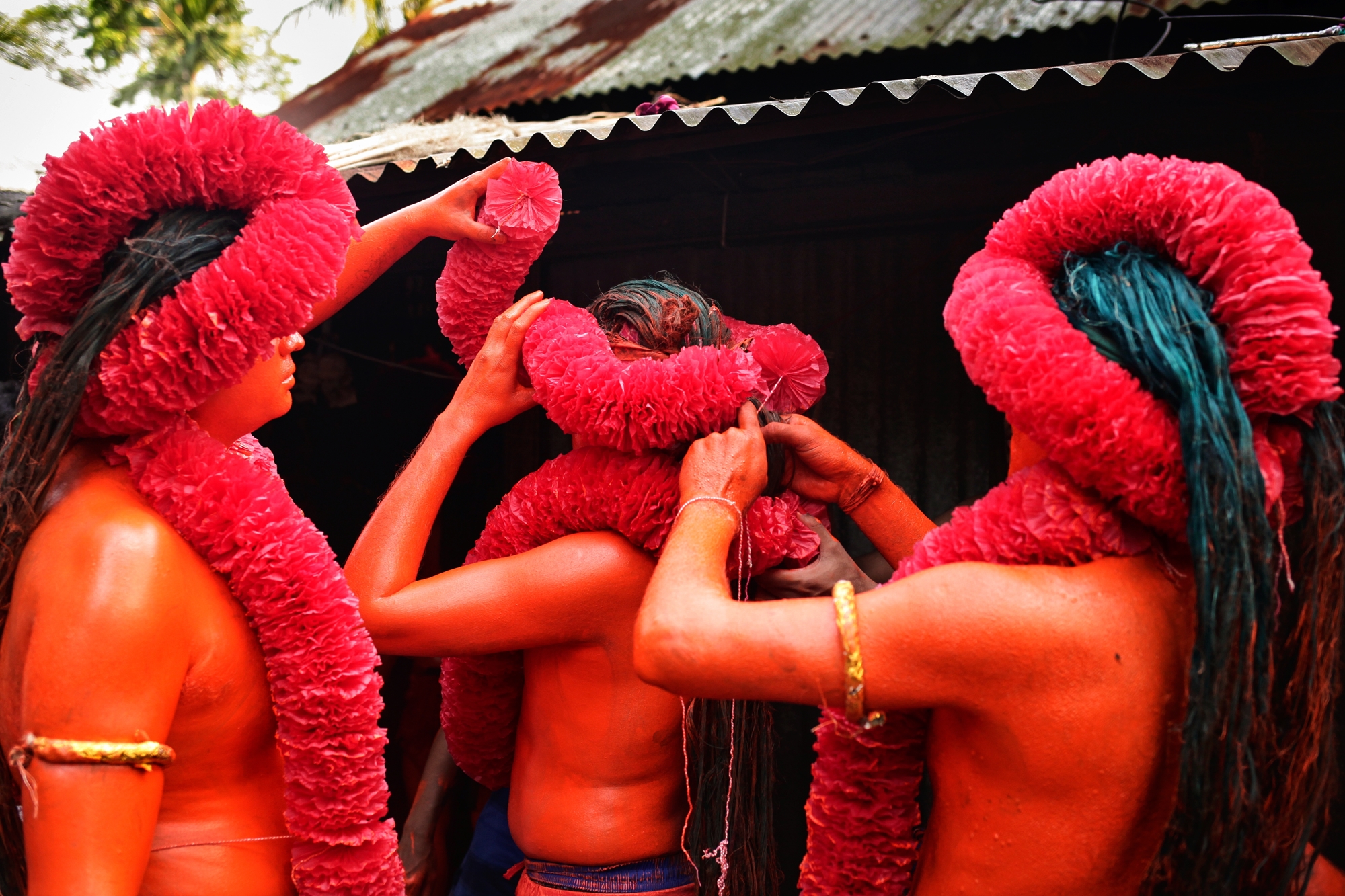Participants in a Lal Kach festival procession get ready for the event. The Hindu youth and men paint themselves with red color and attend a procession holding swords as they show power against evil and welcome the Bengali New Year.
