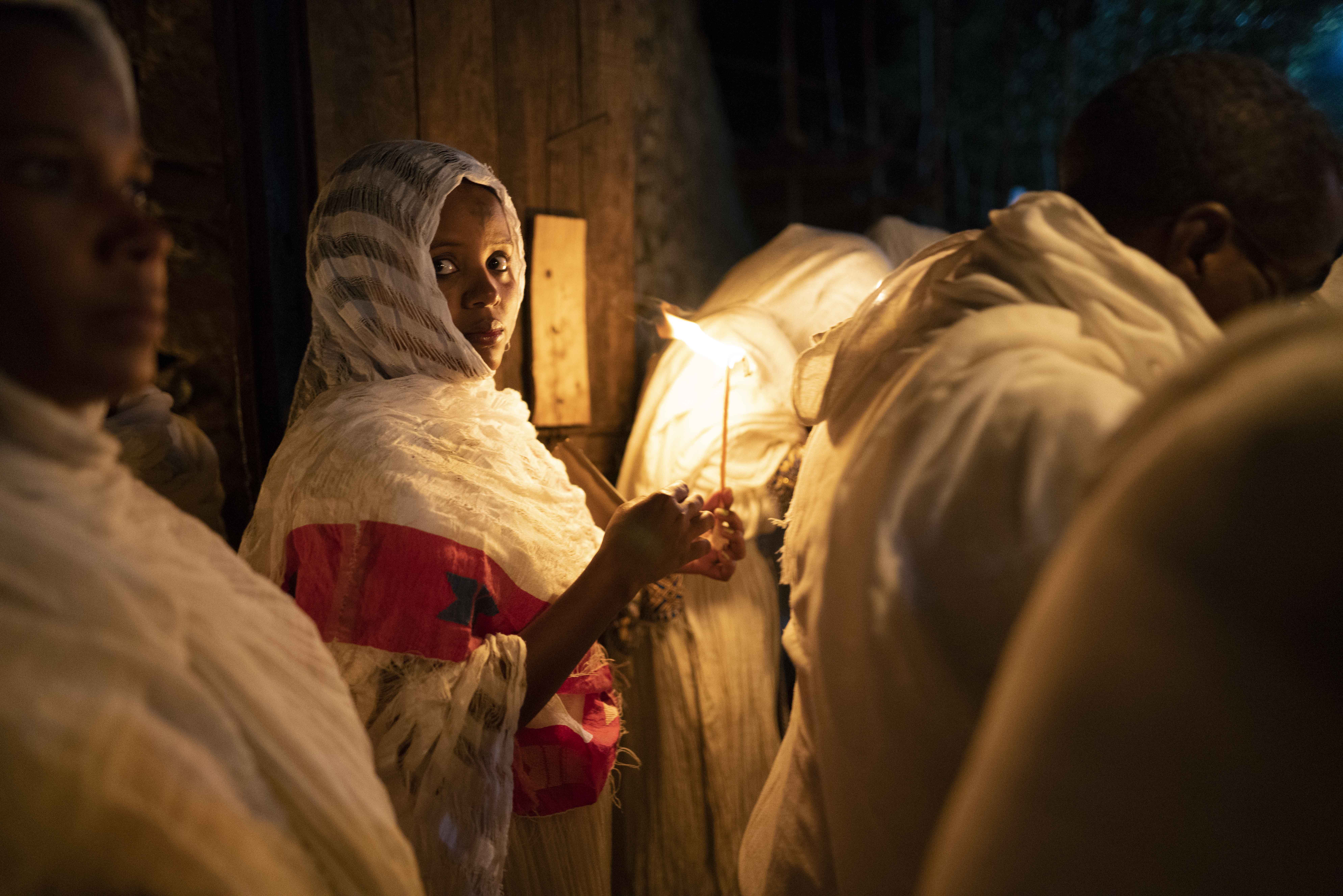 As dawn approaches, more worshippers hurry through the church walls to witness the ceremony, all dressed in their finest clothes. Many women wear a permanent mark of their orthodox faith on their forehead.