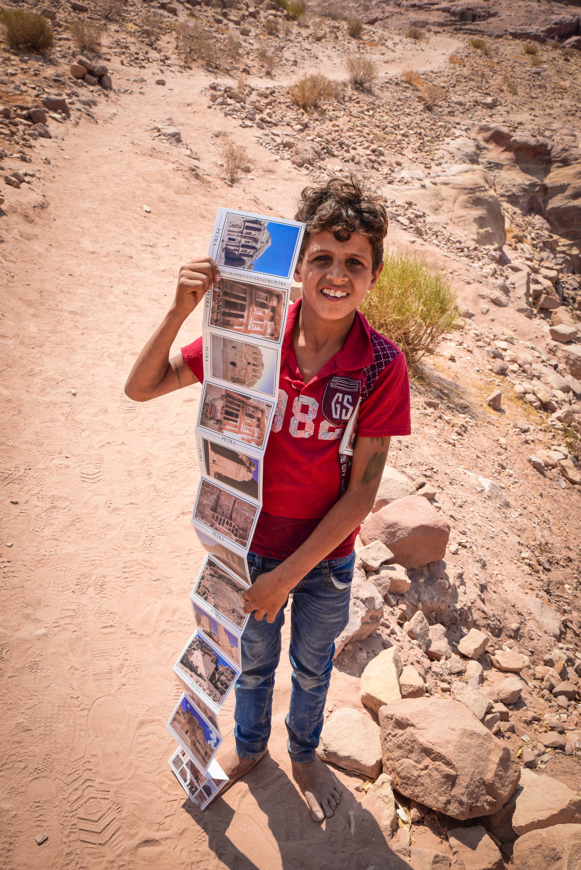 A young boy tries to sell postcards of Petra.