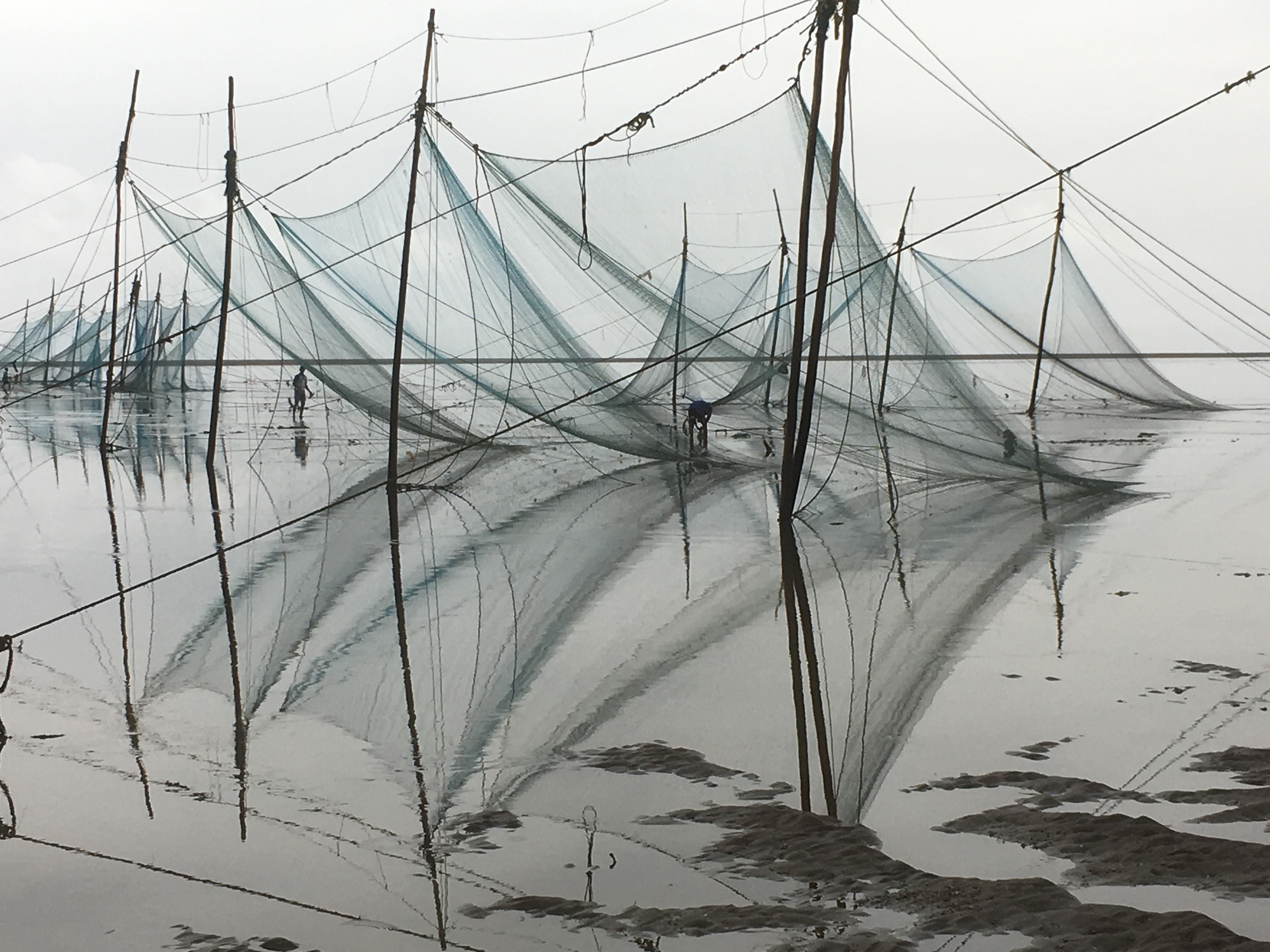 Beautiful reflection of fishing net falling in the Dumas beach water.Dumas is a beach 10 km from Surat.Surat is called Diamond city of India.