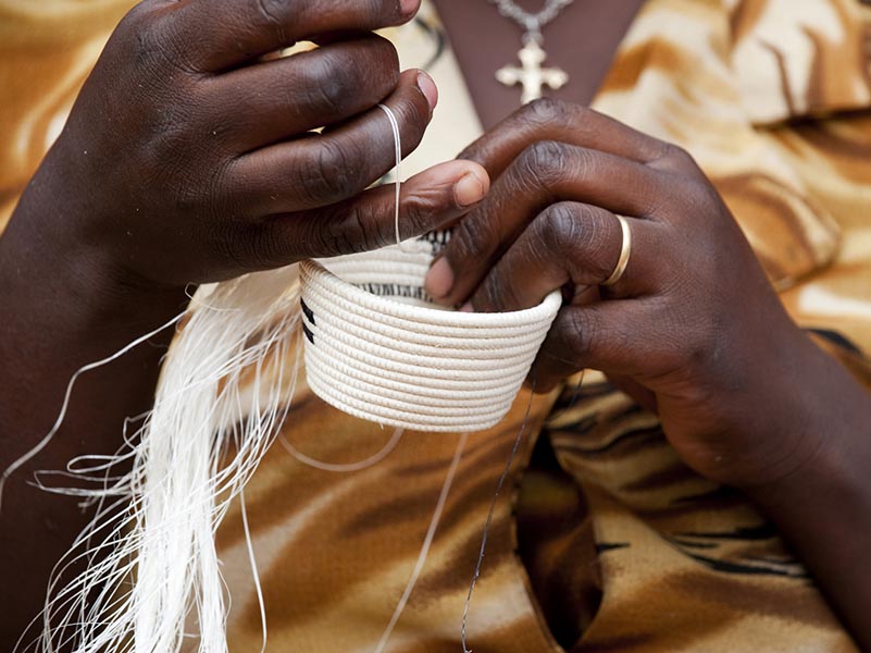 A woman weaves a traditional basket at a women's cooperative in Rwanda.