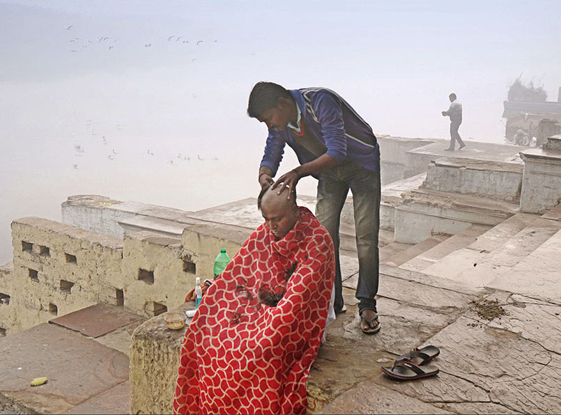 Another integral part of the religion is “Mundan,” or head shaving. It’s a prominent ritual often conducted on the banks of a holy river. Here, a barber can be seen performing this ceremony along the Yamuna. With no fixed premises for his business, he carries it out wherever he can.