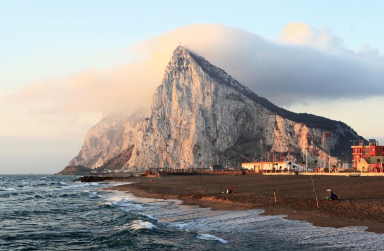The sharp peak and cliffs of Gibraltar as seen from a beach in southern Spain.
