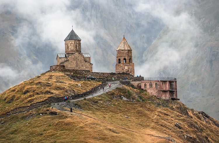 Gergeti Trinity Church sits on it's grassy peak during rainy weather in the Caucasus Mountains Kazbegi, Georgia
