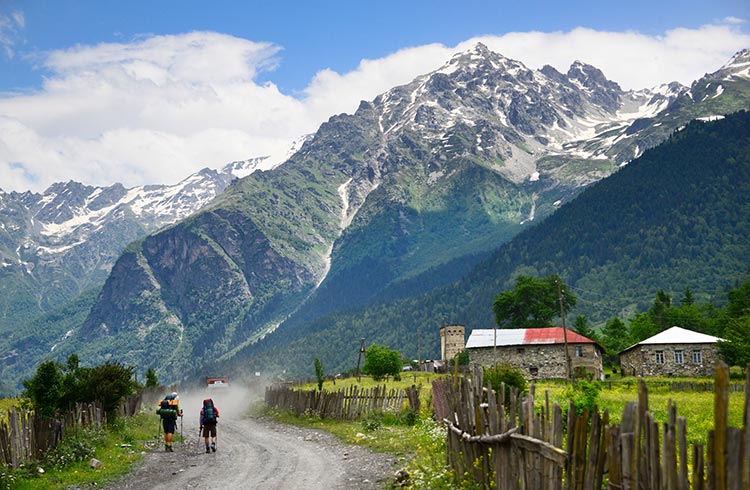 Hikers walking on dirt road at Cholashi village, Zemo Svaneti region, Caucasus mountains
