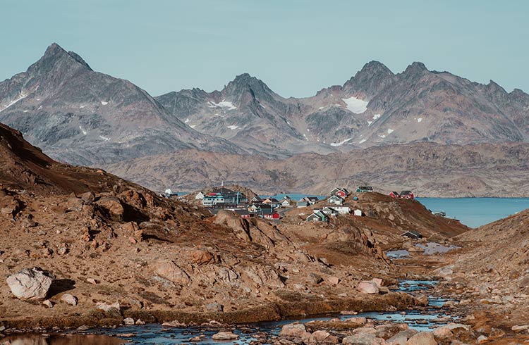 A colorful village sits between mountains in East Greenland