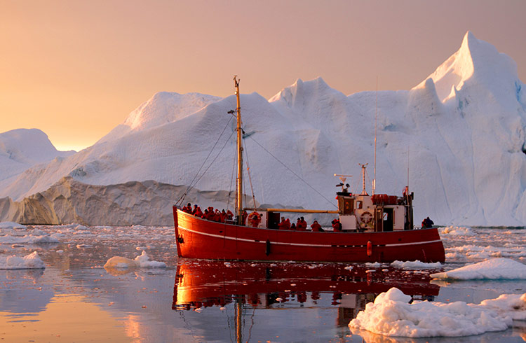 A red cruise ship cuts through the ice in the Arctic in Greenland