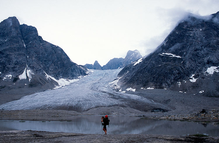 A woman is hiking in front of a glacier